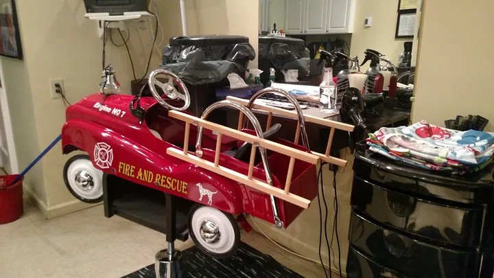 The empty red fire truck chair, Engine No 7, with a wooden ladder and gold Fire and Rescue lettering